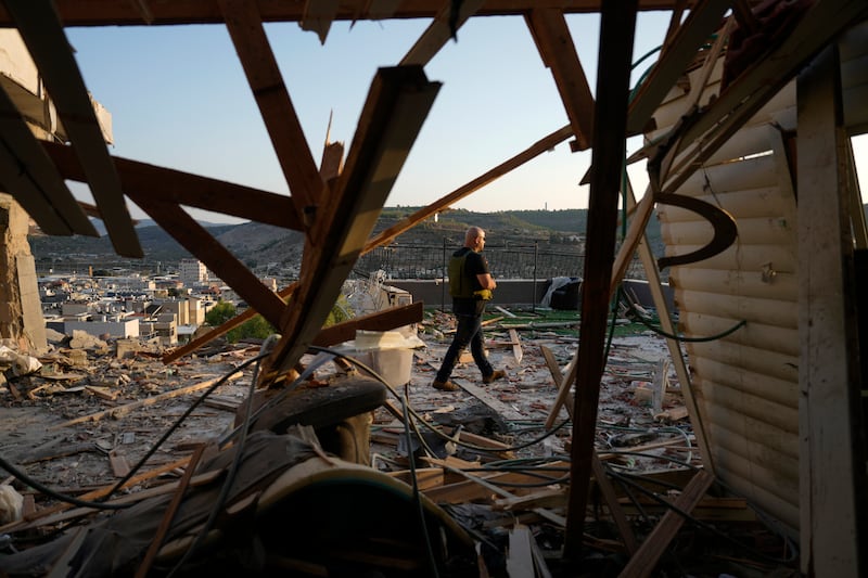 Israeli security forces survey damage to a home in the north of the country which was struck by a rocket fired from Lebanon (Ariel Schalit/AP)