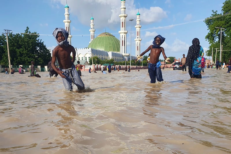 People walk through floodwaters following a dam collapse in Maiduguri, Nigeria (Joshua Olatunji/AP)