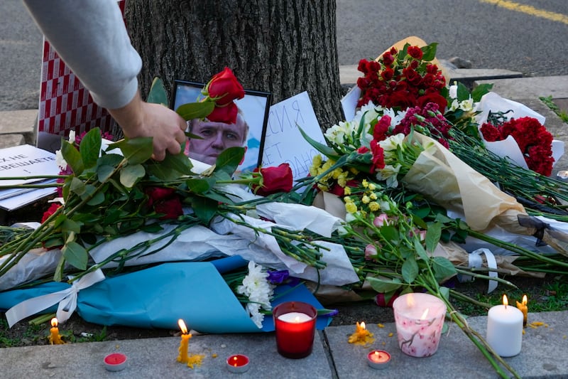 A woman places flowers during protest in front of Russian embassy in Belgrade, Serbia (AP Photo/Darko Vojinovic)