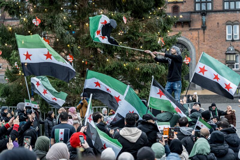 People wave Syrian opposition flags at City Hall Square in Copenhagen, Denmark (Emil Nicolai Helms/Ritzau Scanpix via AP)