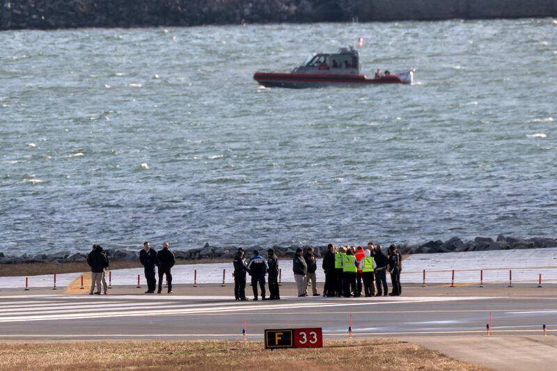 Officials gather at the end of a runway near the wreckage site in the Potomac River of a mid-air collision between an American Airlines jet and a Black Hawk helicopter (Jose Luis Magana/AP)