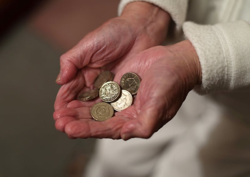 An elderly woman holding pound coins in her hands