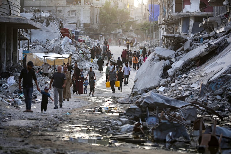 Palestinians displaced by the Israeli air and ground offensive on the Gaza Strip walk through sewage flowing into the streets of Khan Younis, Gaza (Jehad Alshrafi/AP)