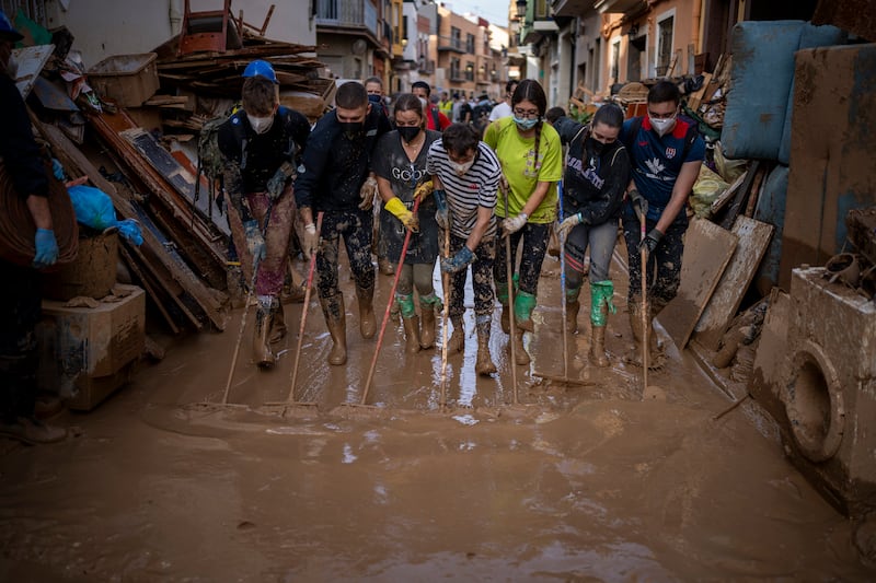 Volunteers and residents clean the mud from the streets in an area affected by floods in Paiporta, Valencia (Emilio Morenatti/AP)