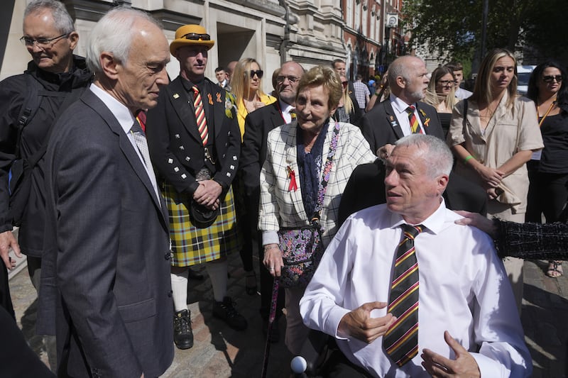 Sir Brian Langstaff, left, speaks to infected blood victims and campaigners outside Central Hall in Westminster, London