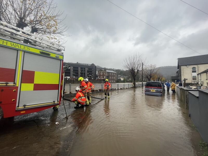 Firefighters pumping water from a street by the River Taff, in Pontypridd, Wales, following flooding on Sunday