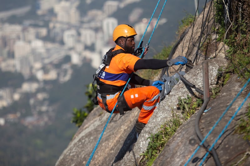 Trash collector Richard Ribeiro rappels down Corcovado Mountain to remove garbage dumped on the slope of the Christ the Redeemer Statue in Rio de Janeiro (Bruna Prado/AP)