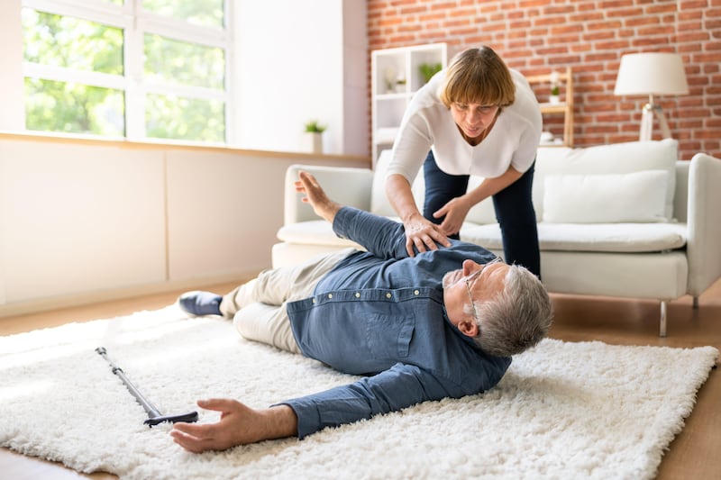 Senior woman helping her husband who has fallen onto the floor