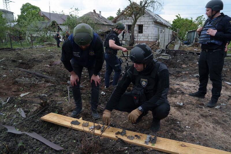 A Ukrainian police officer and war crime prosecutor inspect fragments of a glide bomb in front of damaged house (Evgeniy Maloletka/AP)