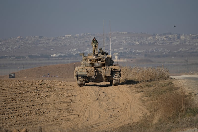 Israeli Defence Forces soldiers work on their tank near the Israel-Gaza border, as seen from southern Israel (Tsafrir Abayov/AP)