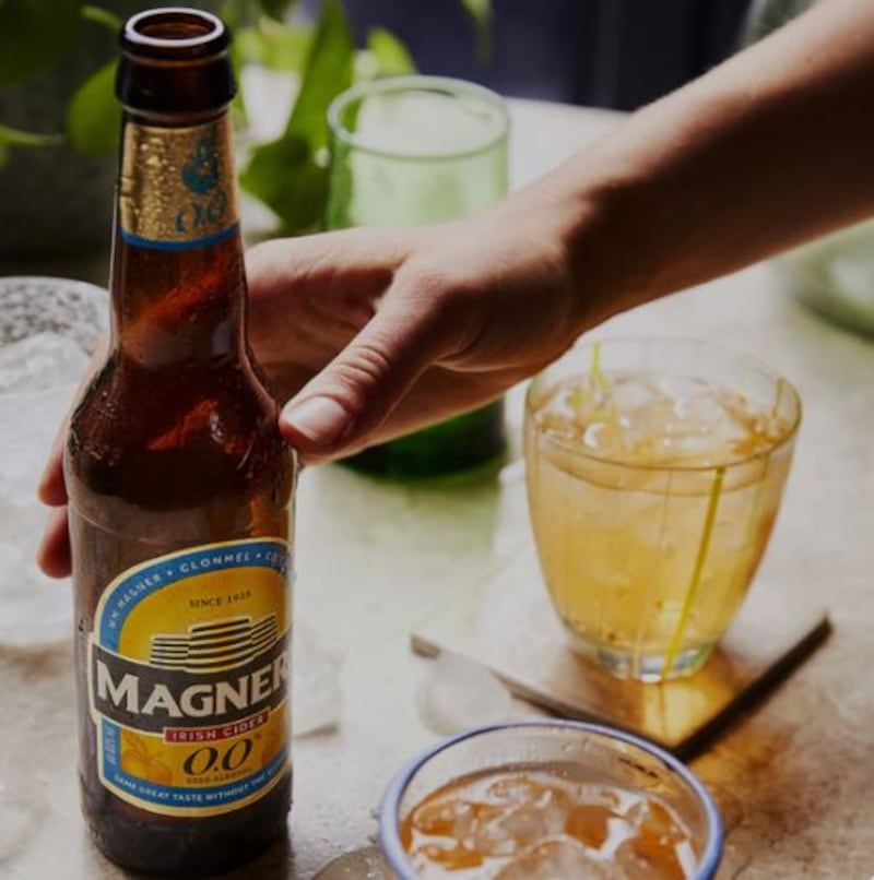 A hand reaching for a Magner's alcohol-free cider