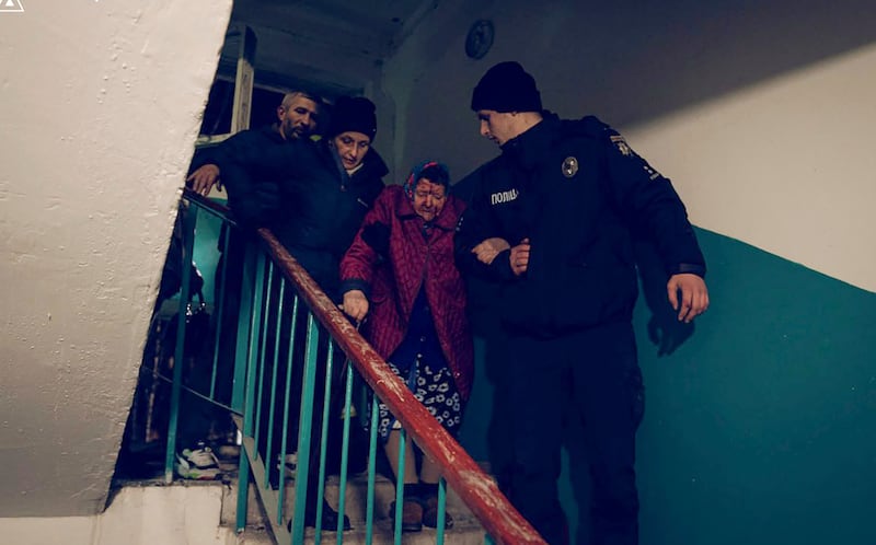 A police officer evacuates an elderly resident following a Russian rocket attack that hit a multistorey apartment building in Sumy, Ukraine (Ukrainian Emergency Service via AP)