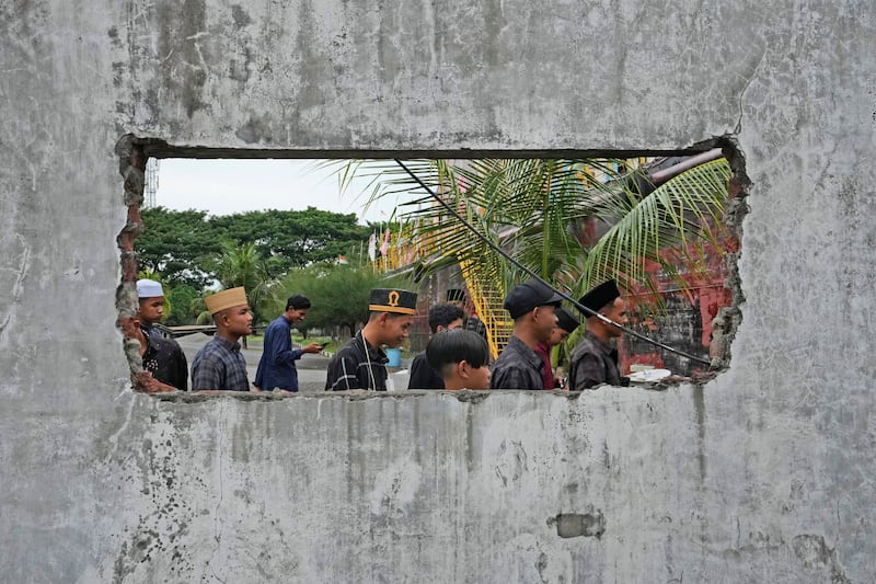 People are seen through a hole in the wall of a building damaged by the tsunami in Banda Aceh (Achmad Ibrahim/AP)