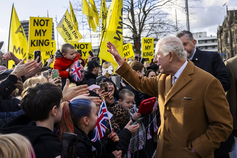 The King meets members of the public, with some anti-monarchy protesters in the background