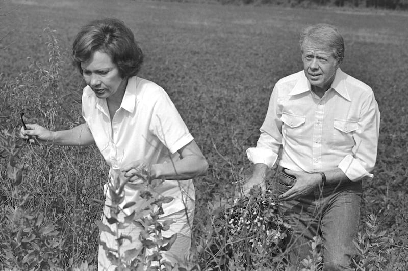 President Jimmy Carter carries a peanut plant as he follows his wife Rosalynn from the field in Webster County, Georgia