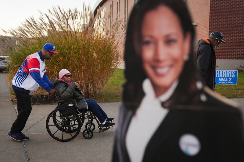 Liza Fortt, centre, accompanied by her son Timothy Walker, left, and husband Willie Fortt, at a polling place at Scranton High School in Scranton, Pennsylvania (Matt Rourke/AP)