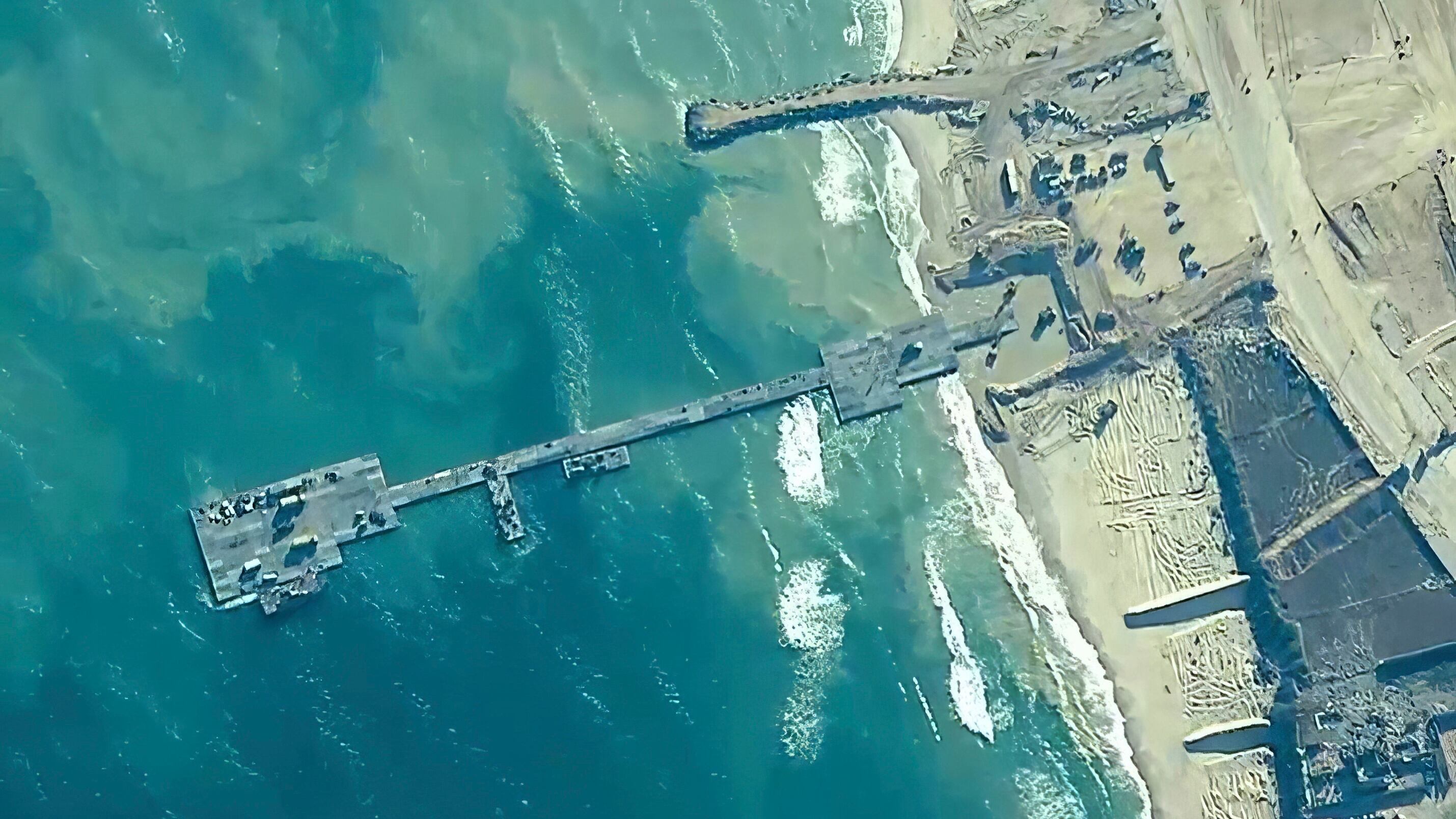 US Army soldiers assigned to the 7th Transportation Brigade (Expeditionary), US Navy sailors assigned to Amphibious Construction Battalion 1, and Israel Defence Forces placing the Trident Pier on the coast of Gaza Strip on May 16 (US Central Command/AP)