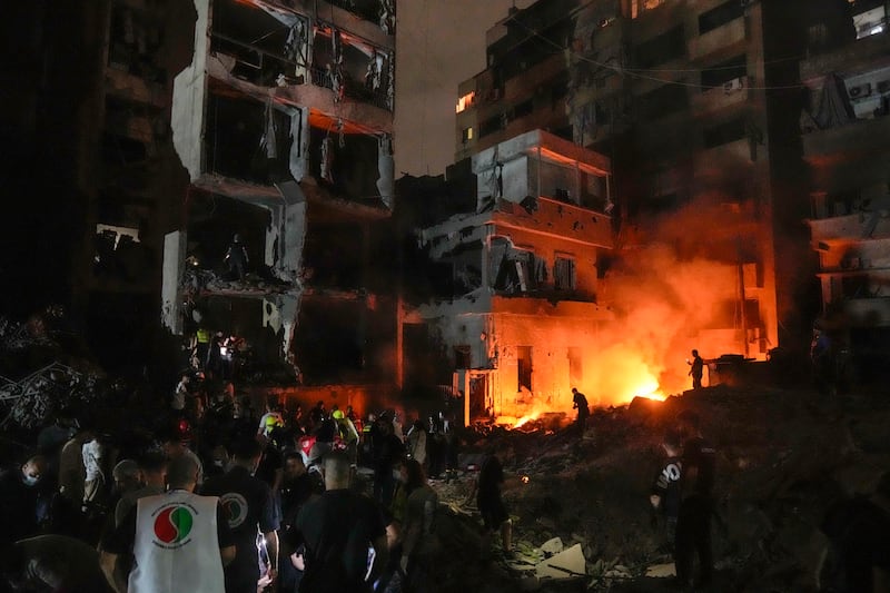 People gather in front of destroyed buildings in central Beirut (Bilal Hussein/AP)