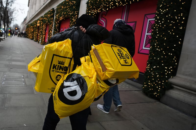 A man carries bags from JD Sports after shopping in the sales in London’s Oxford Street