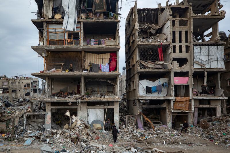 Palestinians sit in their partially standing homes, covered with sheets as makeshift walls, in an area largely destroyed by the Israeli offensive in Jabaliya, Gaza Strip (Jehad Alshrafi/AP)