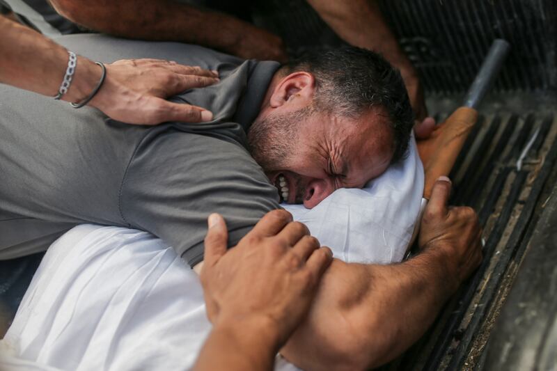 Palestinians mourn over the bodies of relatives killed in an Israeli airstrike, at a morgue in Al-Aqsa Martyrs Hospital in Deir al Balah (Jehad Alshrafi/AP)
