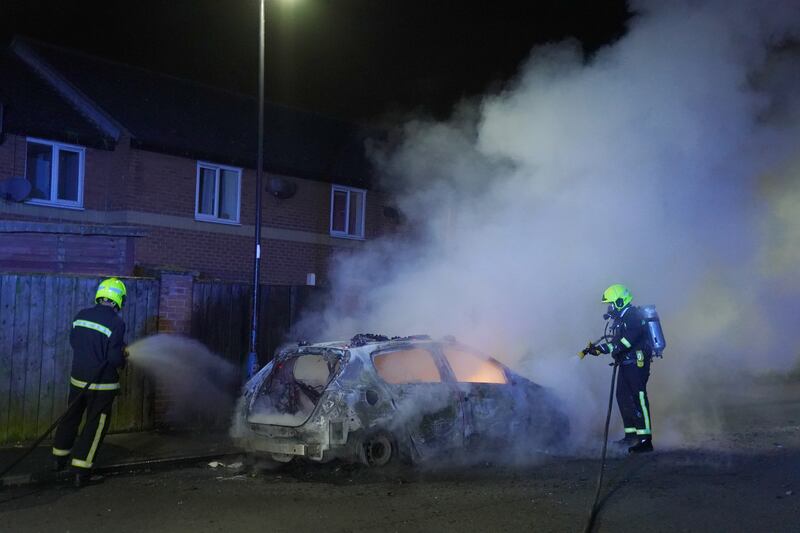 Firefighters attend a burning police car after officers were deployed on the streets of Hartlepool in July