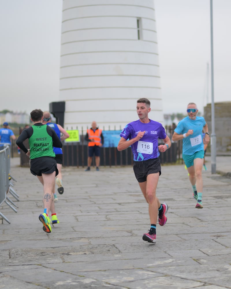 Group of runners in 5k race in front of white lighthouse