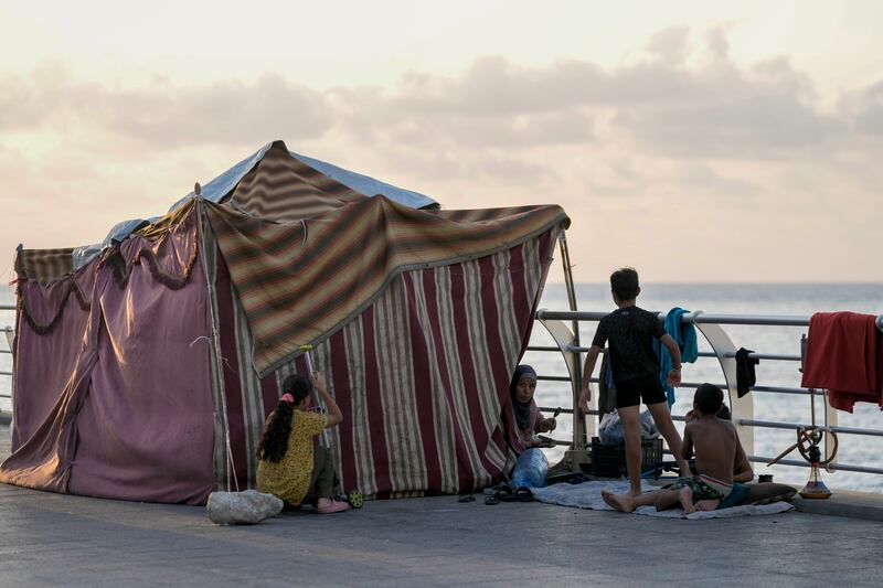 A displaced family fleeing the Israeli air strikes in southern Lebanon sit next to their tent on Beirut’s corniche (Bilal Hussein/AP)