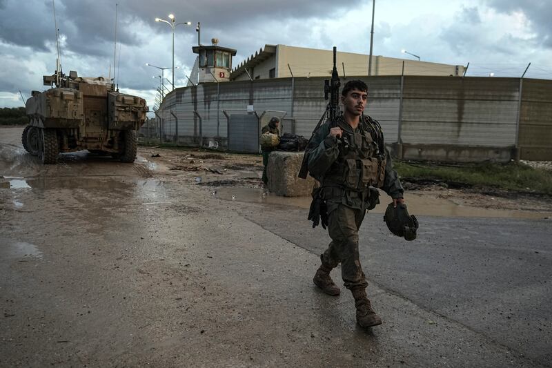 An Israeli soldier walks through a staging area as his unit prepares to enter the Gaza Strip at the Israel-Gaza border in southern Israel (Tsafrir Abayov/AP)