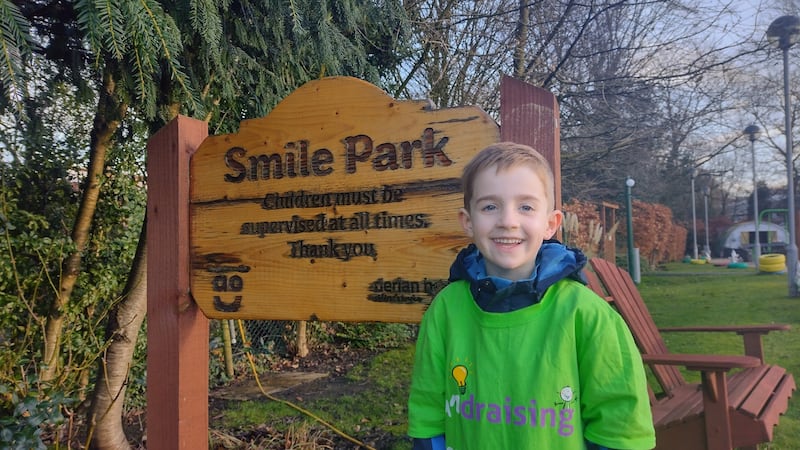 Boy standing in front of a sign and smiling 