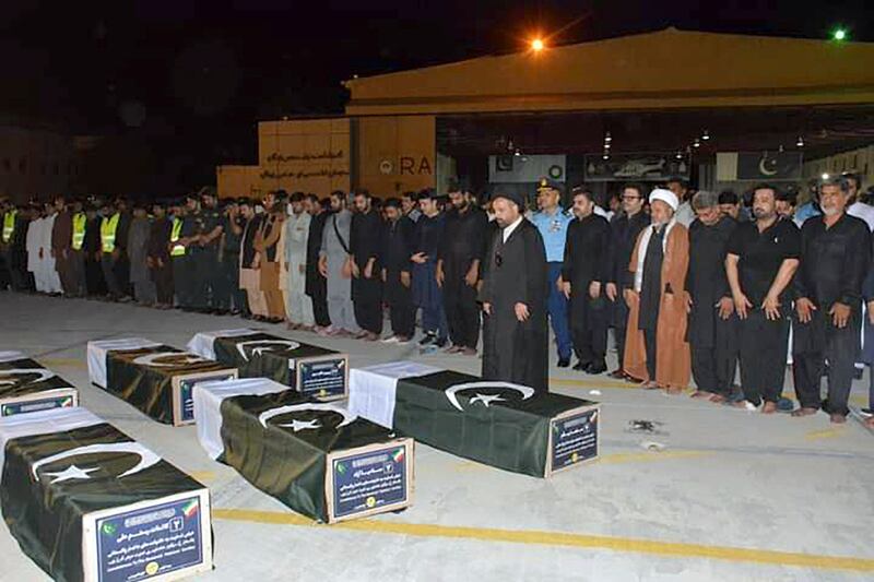 Officials pray after some coffins arrived at an airbase in Jacobabad (Pakistan Air Force/AP)