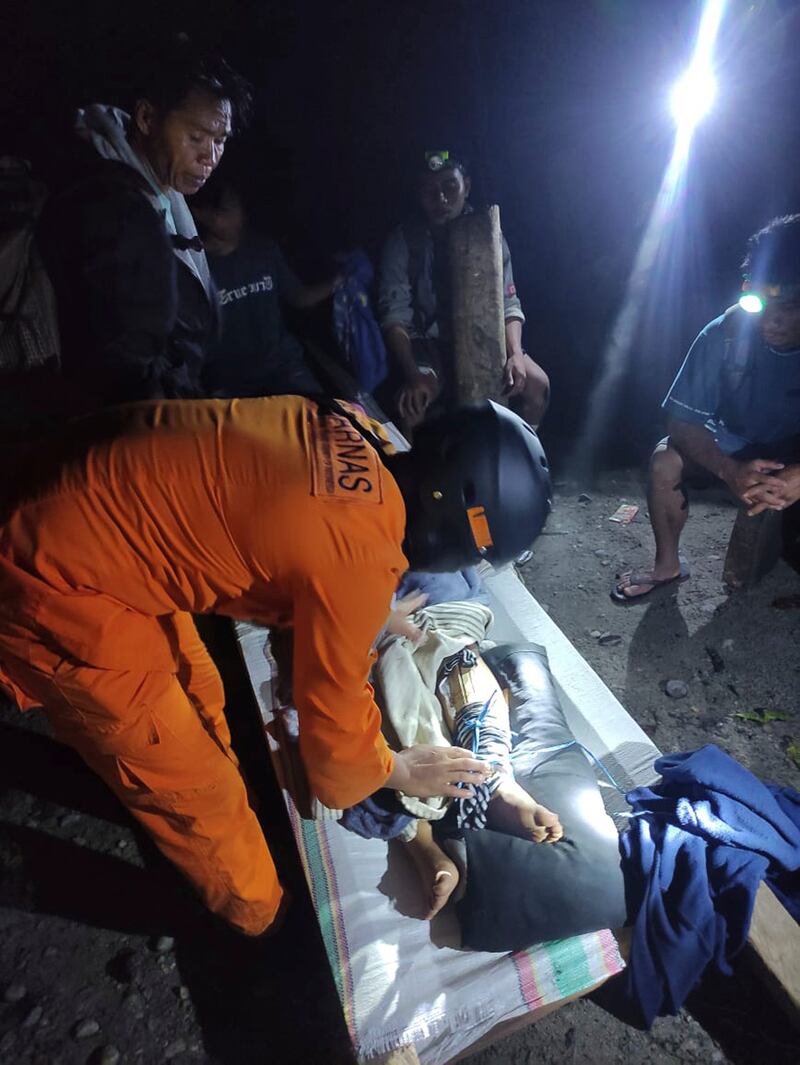 An Indonesian National Search and Rescue Agency worker tends to an injured victim of the landslide in Suwawa on Sulawesi island (BASARNAS/AP)