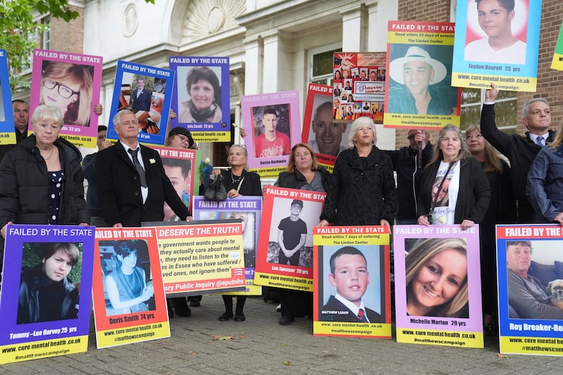 Relatives of people who died after receiving treatment for mental health concerns hold up pictures outside the Lampard Inquiry