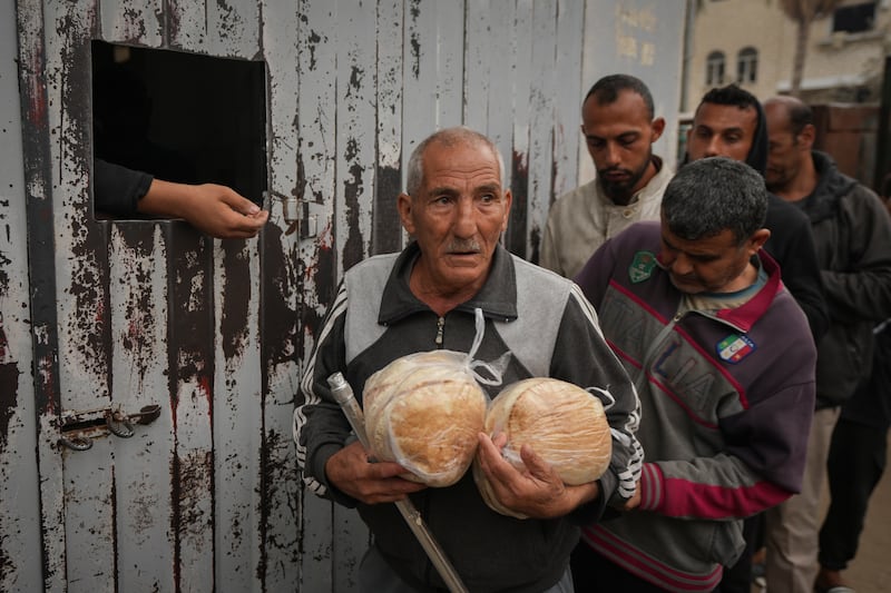 Palestinians collect bread at a bakery in Deir al-Balah, Gaza Strip (Abdel Kareem Hana/AP)