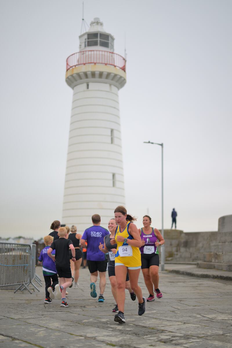 Group of runners in 5k race in front of white lighthouse