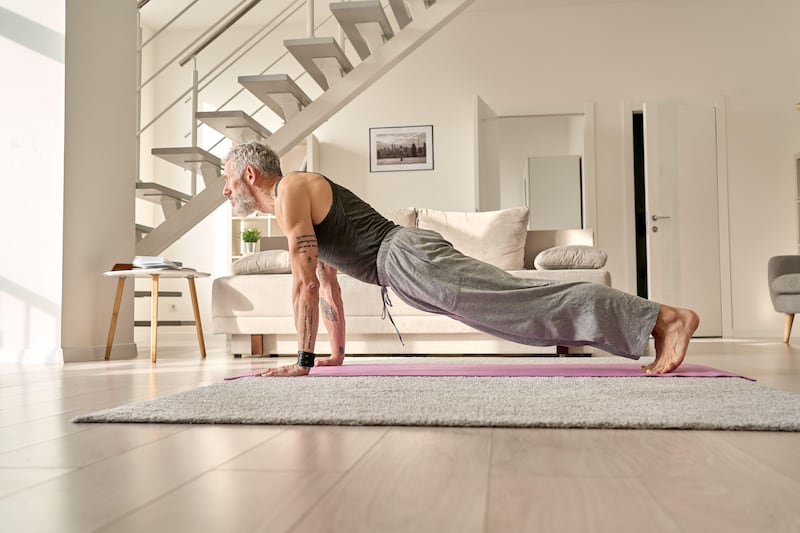 Mature man doing a plank on yoga mat at home