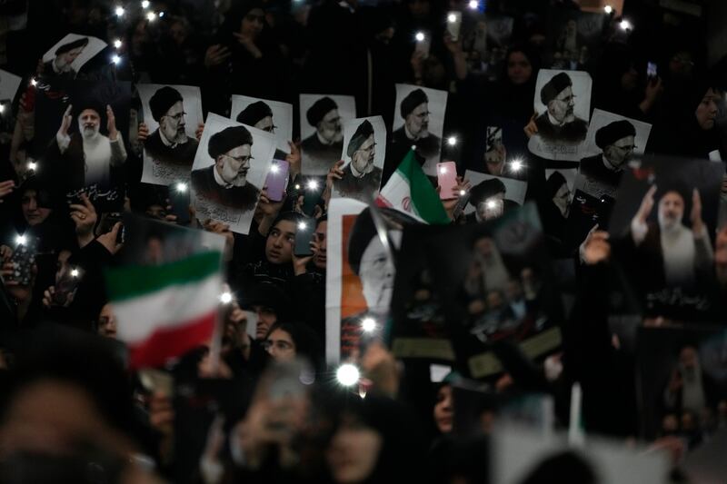 Mourners hold up a posters of the late Iranian President Ebrahim Raisi at the Mam Khomeini Grand Mosque in Tehran (Vahid Salemi/AP)