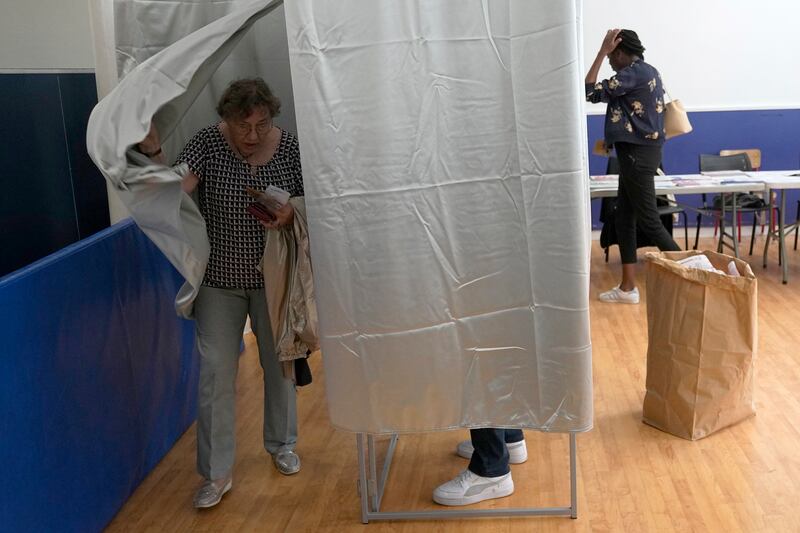 A woman exits a voting booth in Paris, France (Michel Euler/AP)