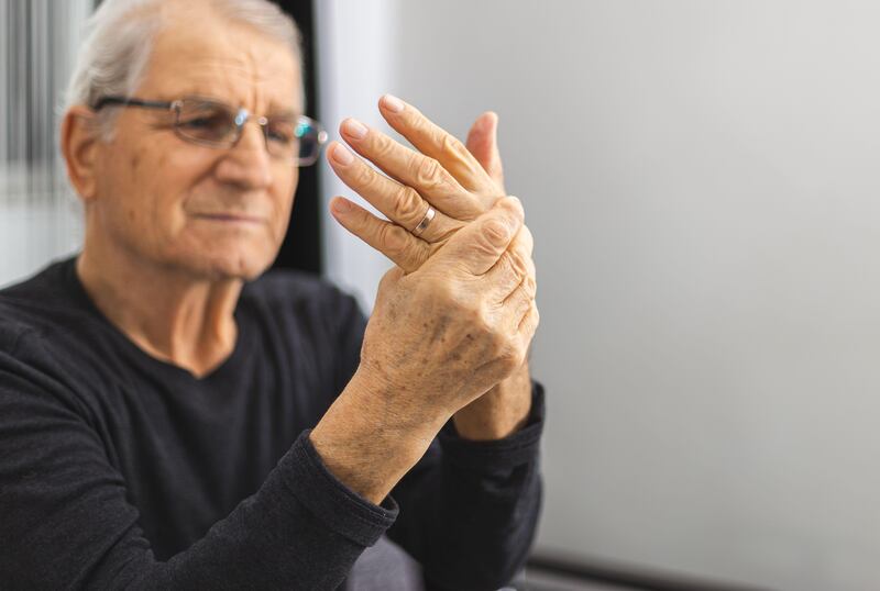 Elderly person massaging his hands