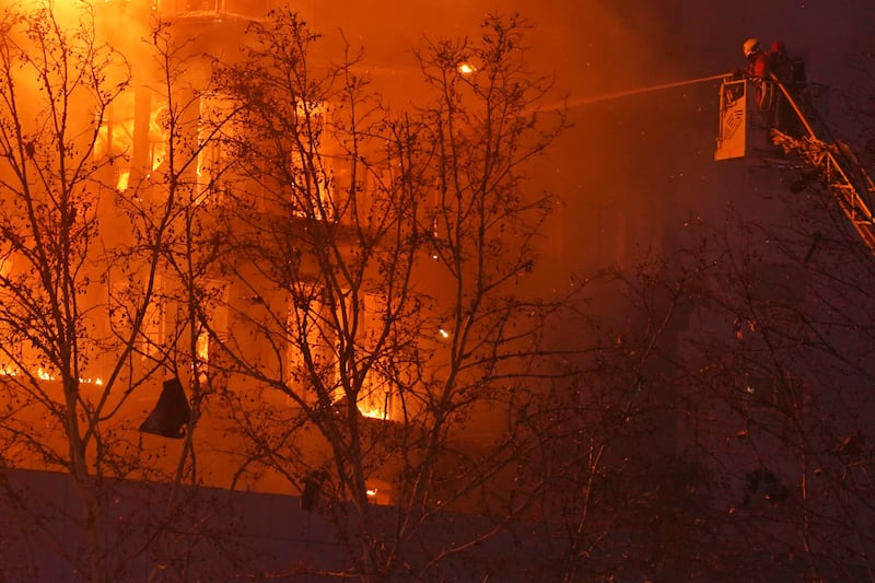 Firefighters spray water on a housing block as it burns in Valencia (Alberto Saiz/AP)