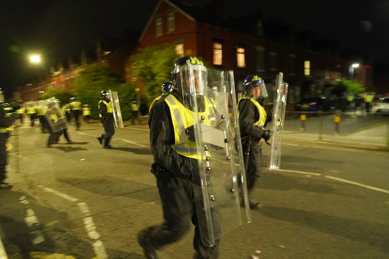 Videos on social media show a crowd of people in a street, with one showing a youth throwing objects at a line of police in riot gear holding shields