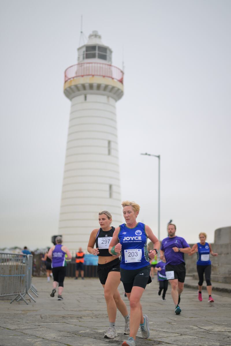 Group of runners in 5k race in front of white lighthouse