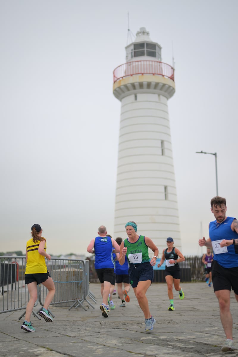 Group of runners in 5k race in front of white lighthouse