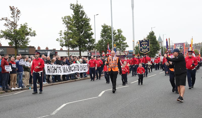 A parade passes the Ardoyne shop fronts from  the Woodvale area in North Belfast on Saturday Morning , as protesters line the street.PICTURE COLM LENAGHAN