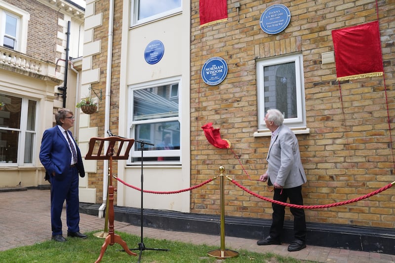 DJ Mike Read watches as Johnny Mans, who represented Sir Norman Wisdom, unveils a Blue Plaque in his name during a multi-plaque unveiling ceremony