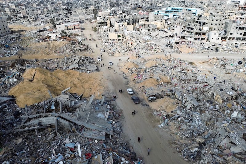 Palestinians walk through the destruction in Rafah, as a ceasefire deal between Israel and Hamas went into effect (Jehad Alshrafi/AP)