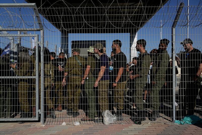 Israeli soldiers gather at the gate to the Sde Teiman military base, as people protest in support of soldiers being questioned for detainee abuse (Tsafrir Abayov/AP)