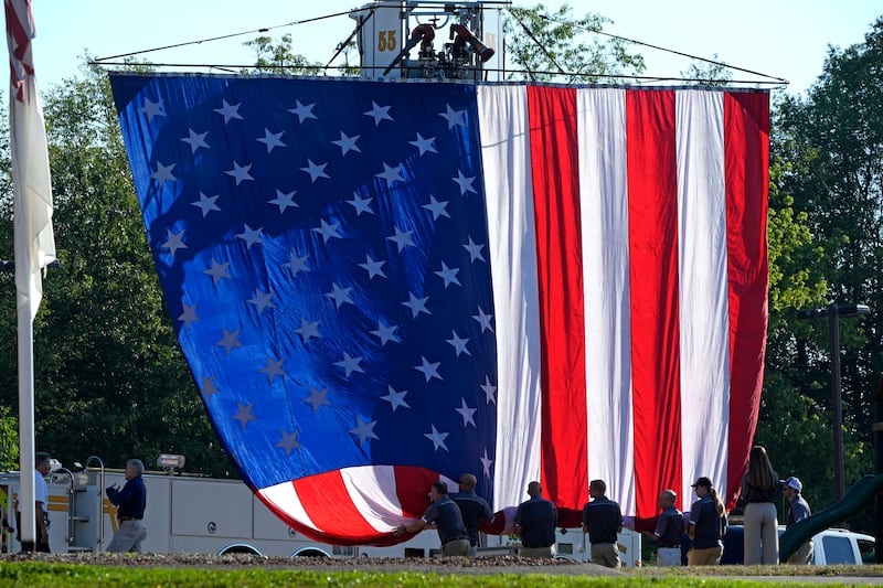 A giant American flag is unfurled outside the Cabot Church (Gene J Puskar/AP)