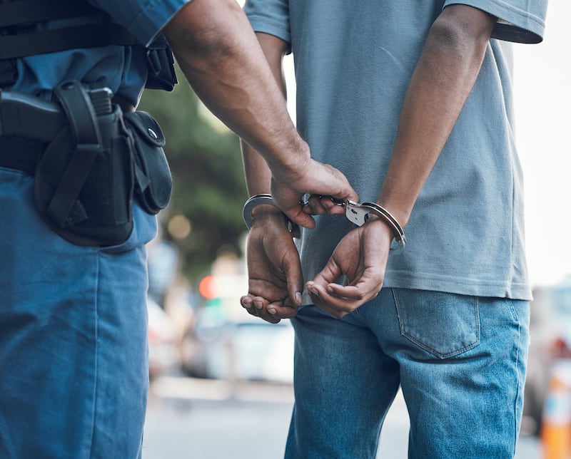 Handcuffs, police and hands of police man with criminal in city for justice, crime or corruption. Illegal, arrest and law enforcement officer with suspect, thief or gangster for jail, robbery or fail