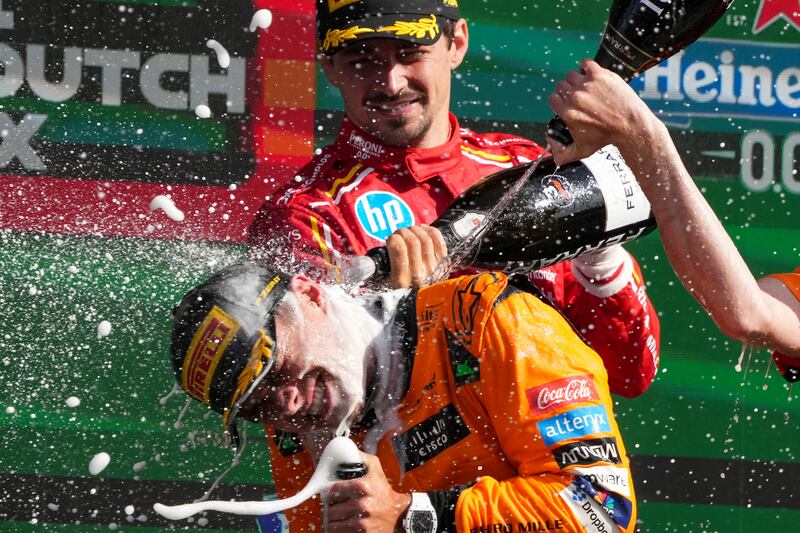 Norris is sprayed with champagne after his triumph (Peter Dejong/AP)